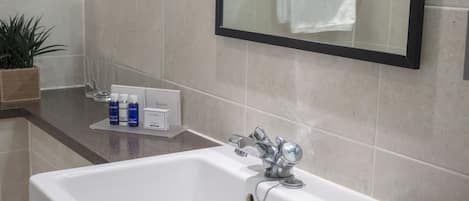 A bathroom with a white sink, a mirror, and toiletries on the counter.
