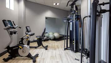 A gym with cardio machines, weightlifting equipment, and exercise balls.