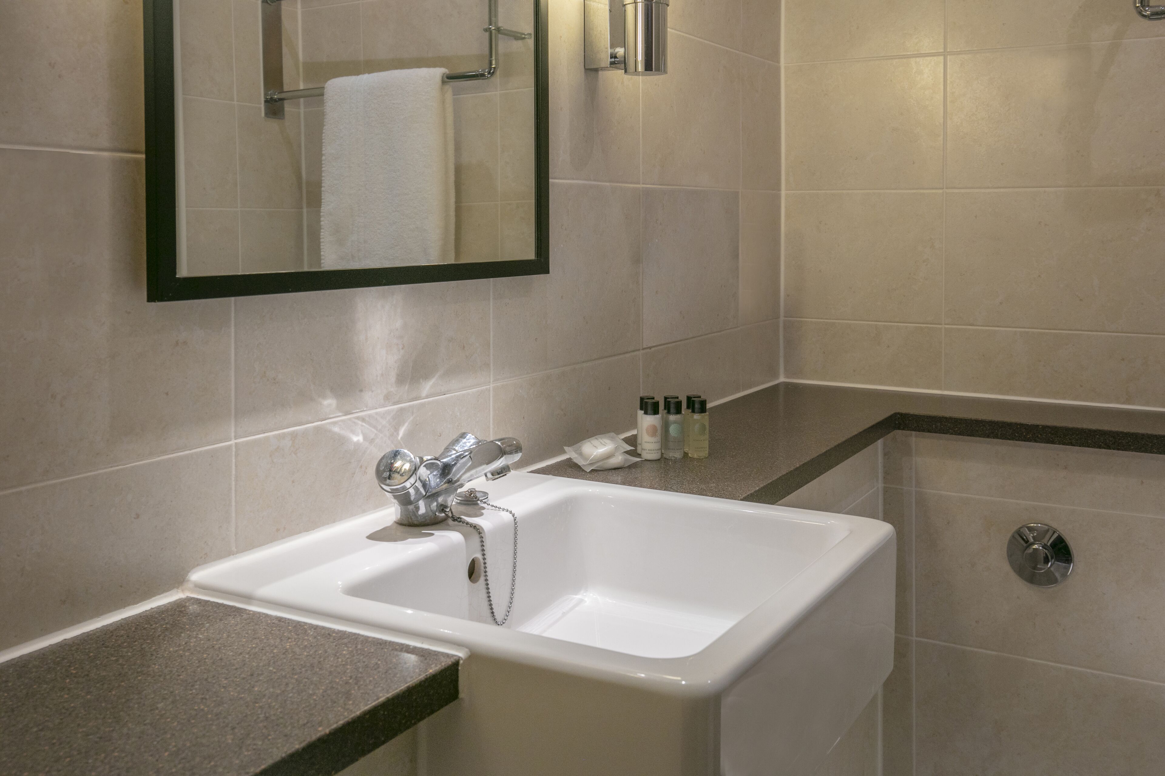 A bathroom with a white sink, a mirror, and a shower.