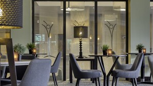 Un comedor moderno con sillas tapizadas en gris, una mesa redonda y una lámpara decorativa.