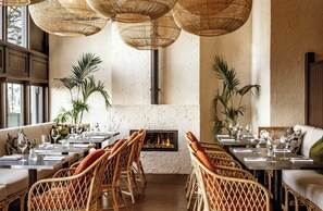 A restaurant with wicker furniture, a fireplace, and large windows. - Leonardo Royal Hotel Bristol - formerly The Bristol Hotel (Bristol)