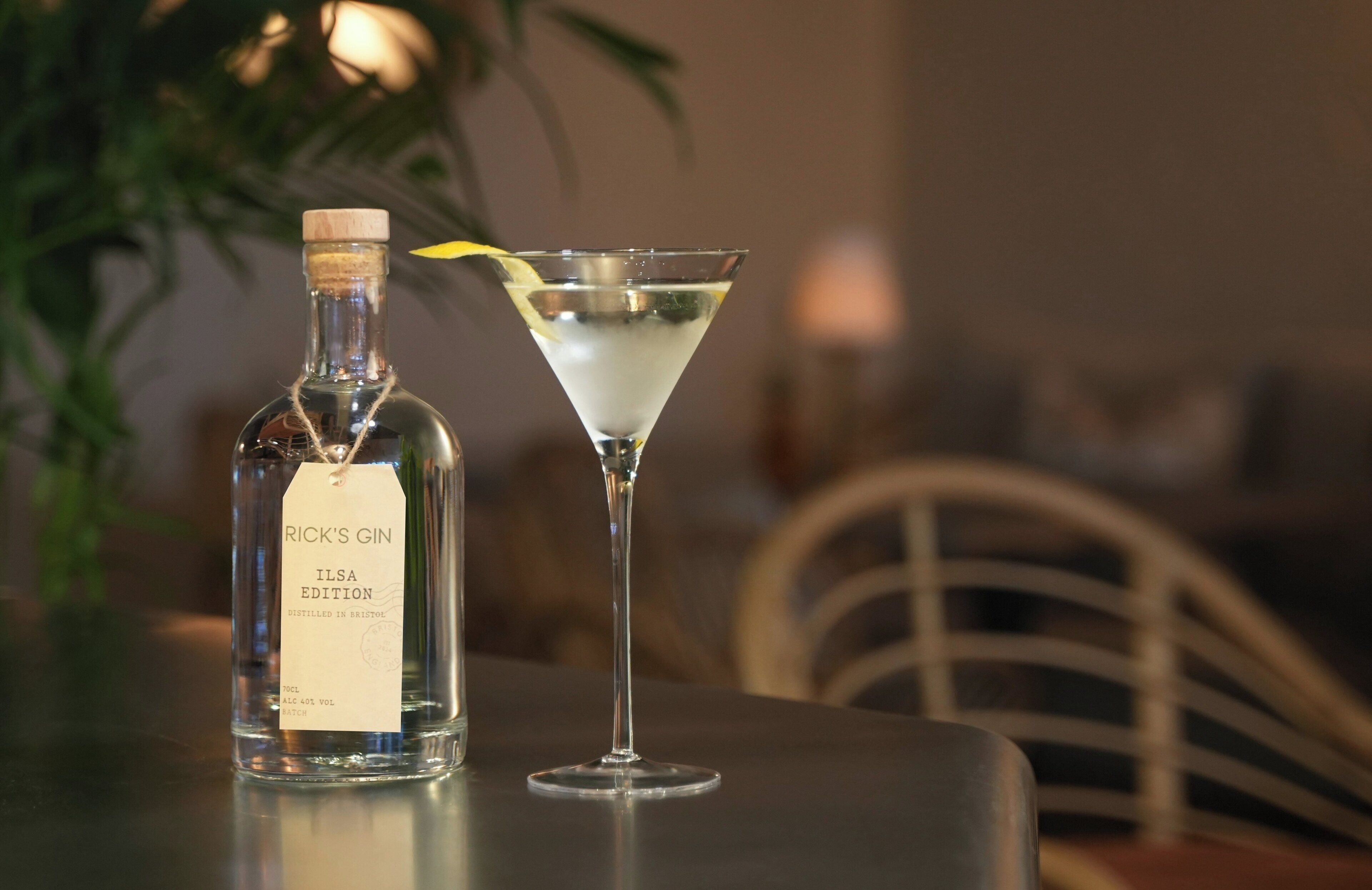 A bottle of Rick's Gin ILSA Edition and a martini glass on a table.