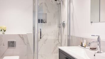 A modern bathroom with a glass-enclosed shower, a white toilet, and a vanity with a mirror.
