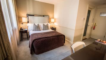 Une chambre d’hôtel avec un grand lit, des lampes de chevet, un bureau et une chaise.