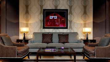 A living room with a sofa, two armchairs, a coffee table, and a framed artwork on the wall.