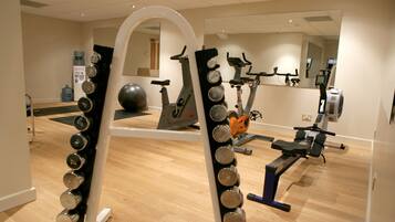 Een sportschool met trainingsapparatuur, een waterdispenser en een grote spiegel.