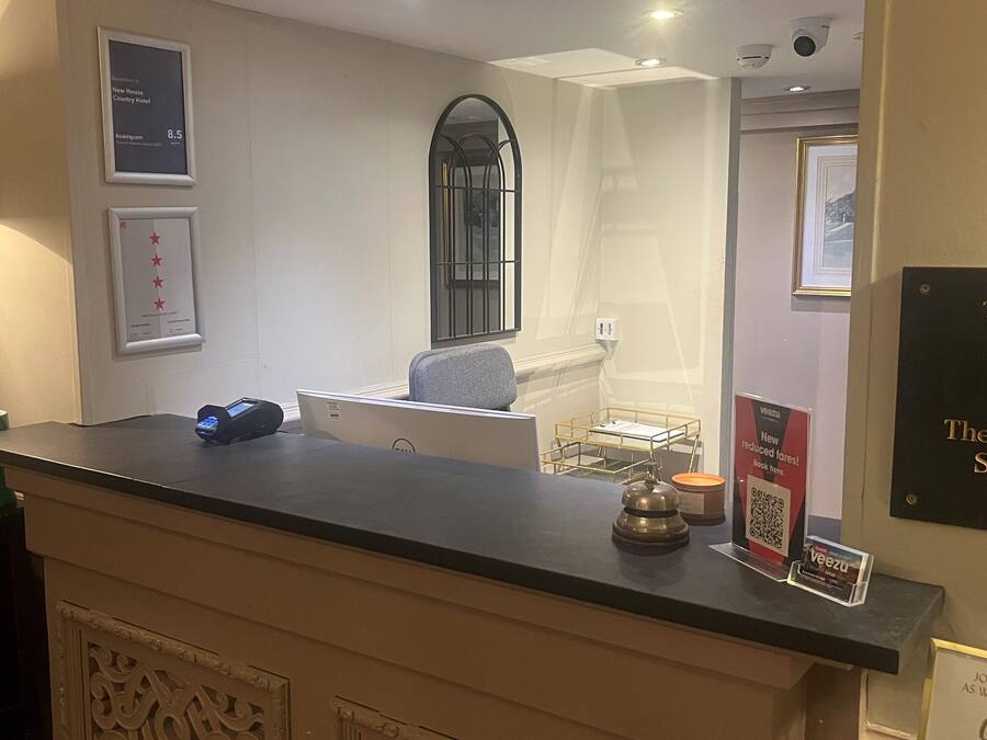 A reception desk with a digital payment terminal, framed awards, and a plaque commemorating the Rt. Hon. Peter Osborne, Secretary of the 27th National Convention.