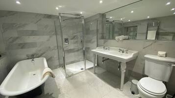 Un baño moderno con ducha envuelta en vidrio, una bañera independiente, un lavabo pedestal y un inodoro.
