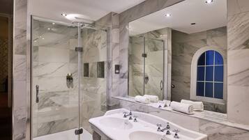 A modern bathroom with a glass-enclosed shower, a large mirror, and a double sink.