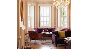 A room with large windows, a chandelier, and a seating area with a table. - New House Country Hotel (Cardiff)