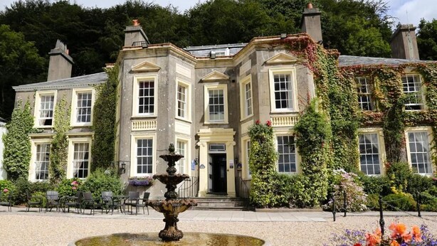 A historic building with a central fountain, surrounded by a gravel courtyard and various plants. - New House Country Hotel (Cardiff)