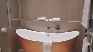 A modern bathroom with a freestanding bathtub, a towel rack, and a hand dryer.