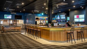 A bar area with a pool table, bar stools, and multiple screens displaying content. - El Toro Motel (Warwick Farm)