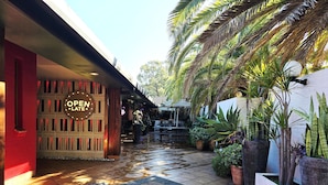 A wet tiled pathway leading to a building with a 'OPEN LATELY' sign. - El Toro Motel (Warwick Farm)