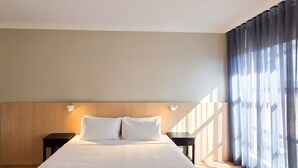 A hotel room with a large bed, two bedside tables, and a view through sheer curtains. - El Toro Motel (Warwick Farm)