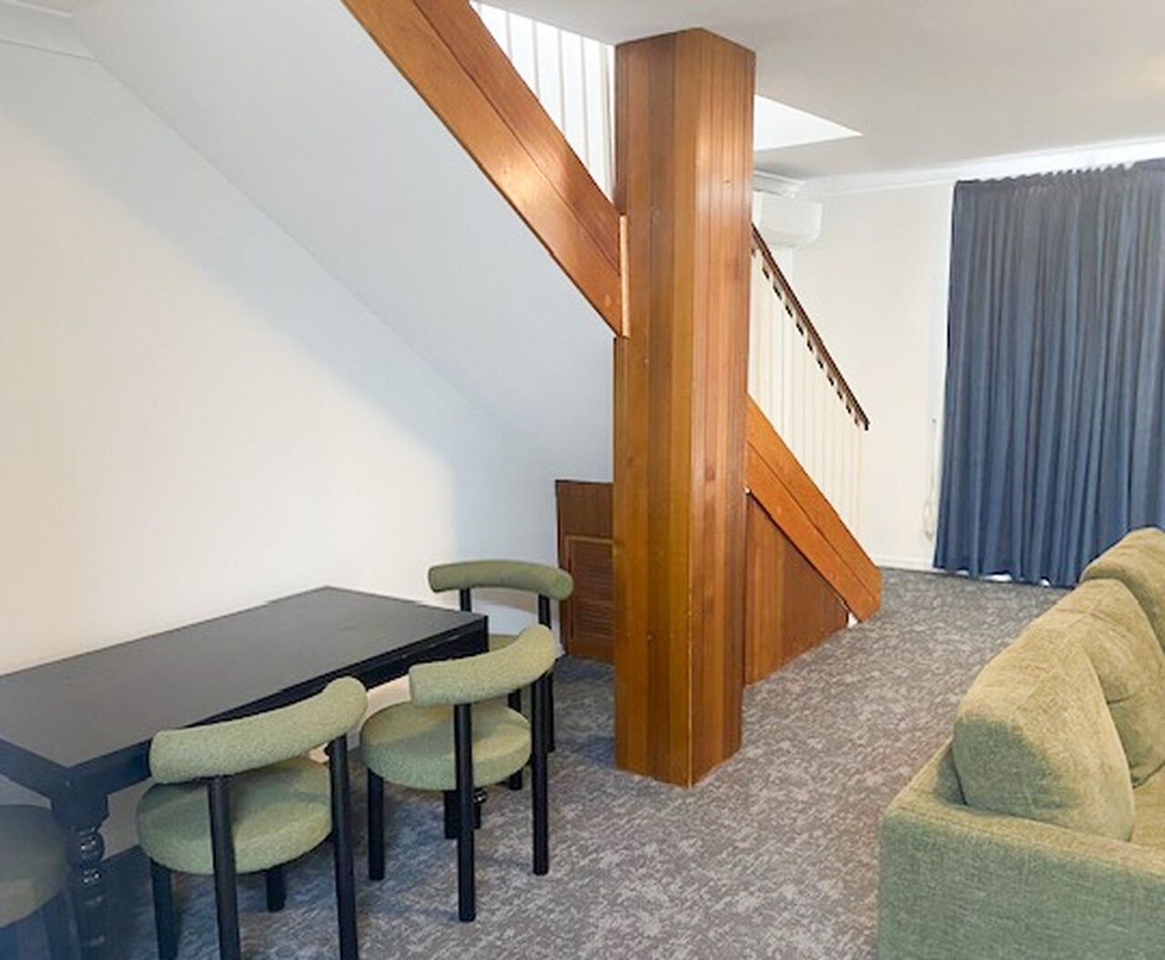Une pièce comprenant une table à manger et des chaises, un escalier et un canapé.
