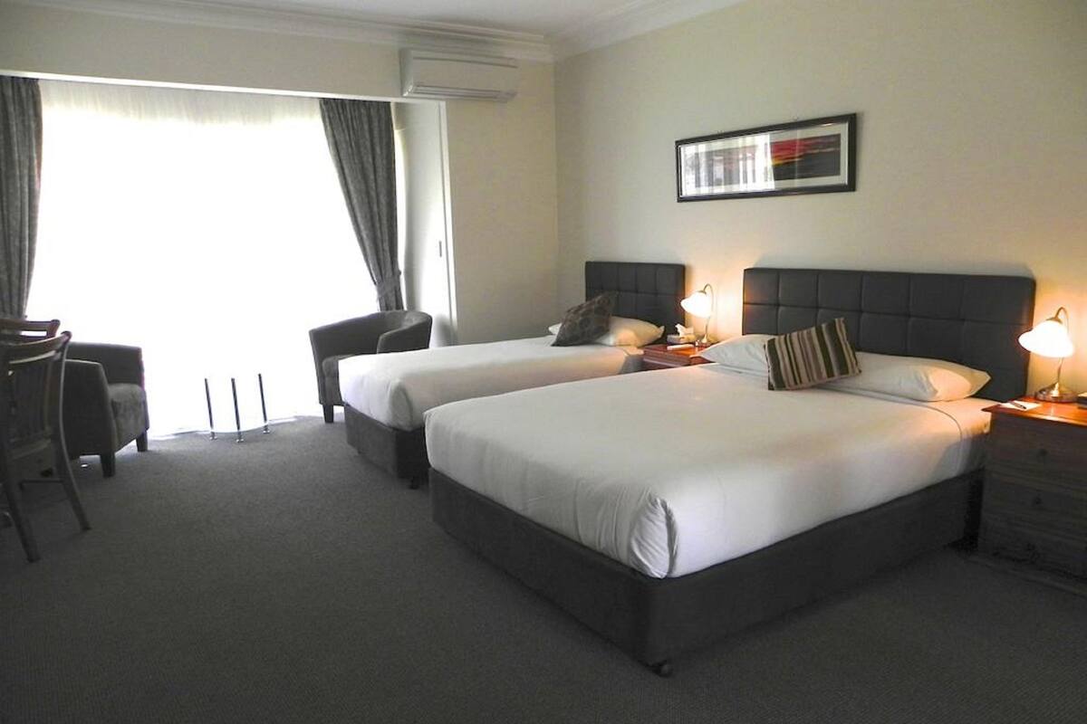 A hotel room with two beds, a desk, and a chair.