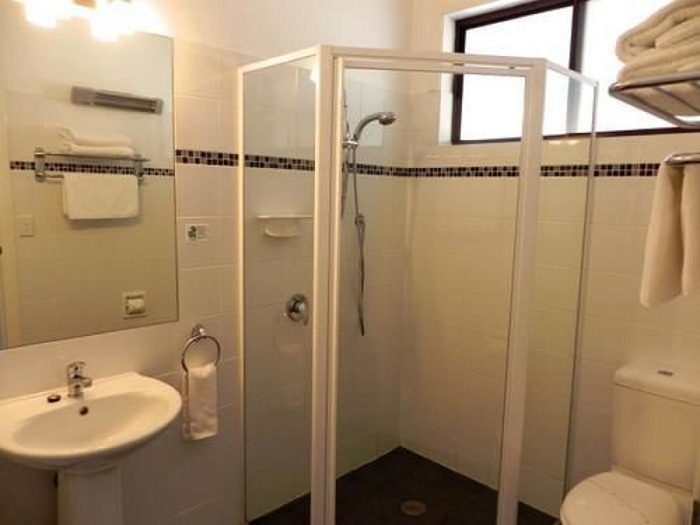 Un baño con ducha de mampara, lavabo e inodoro.