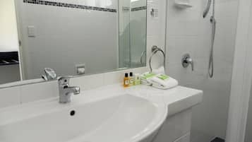 A modern bathroom with a white sink, a large mirror, and a shower.