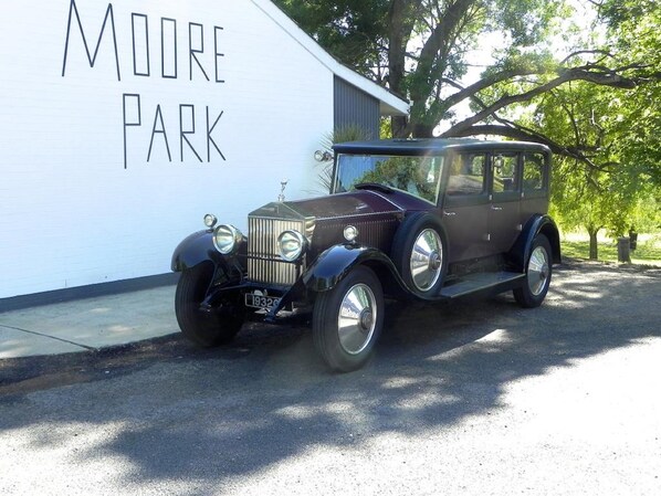 A vintage car parked in front of a building with the sign "MOORE PARK".