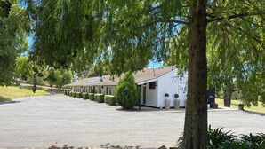 A row of motel rooms with a paved driveway and a small parking area. - Moore Park Inn (Armidale)