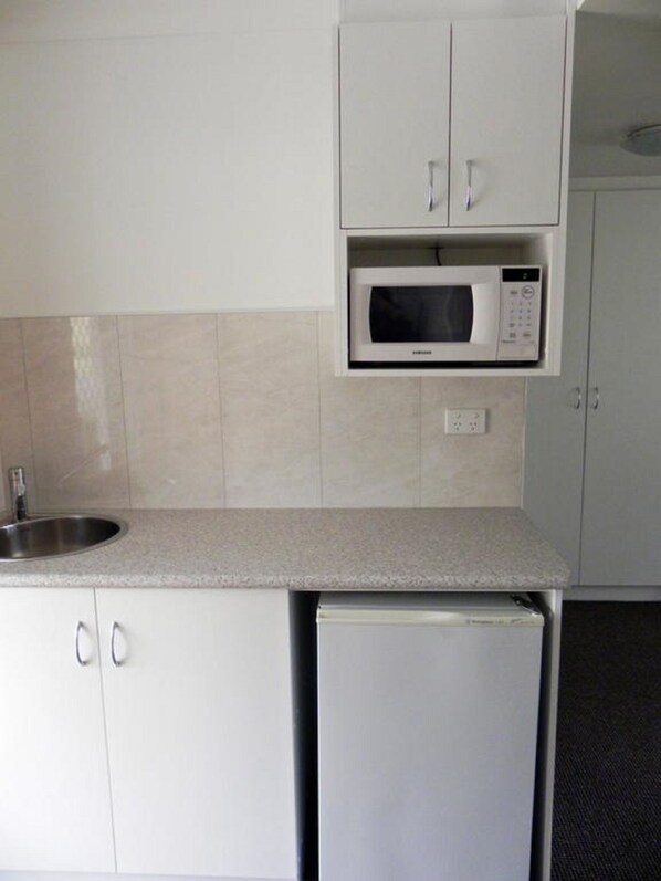 A kitchen with white cabinets, a built-in microwave, a sink, and a dishwasher.
