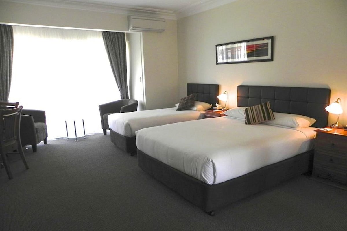 Habitación de hotel con dos camas, un escritorio y una silla.
