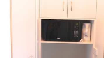 A kitchen with white cabinets, a black microwave, and a coffee maker on the countertop.