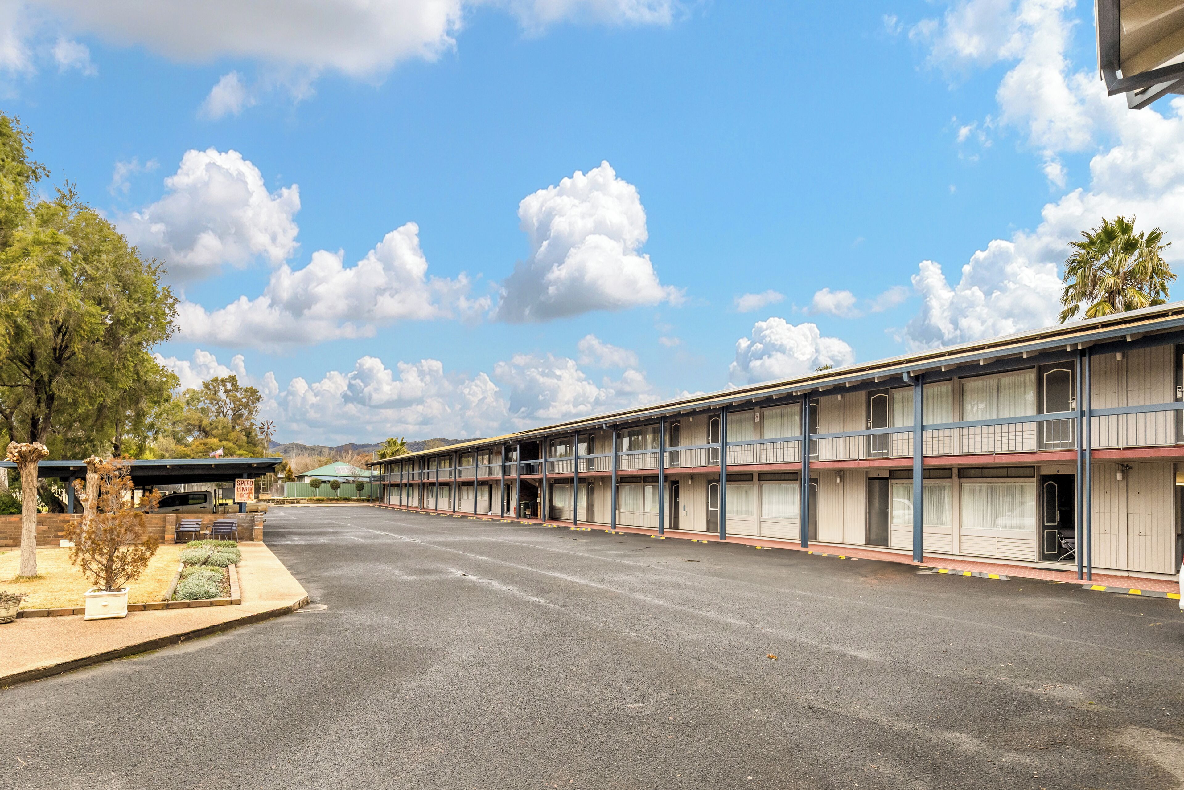 A motel with multiple floors, outdoor seating, and a parking lot.