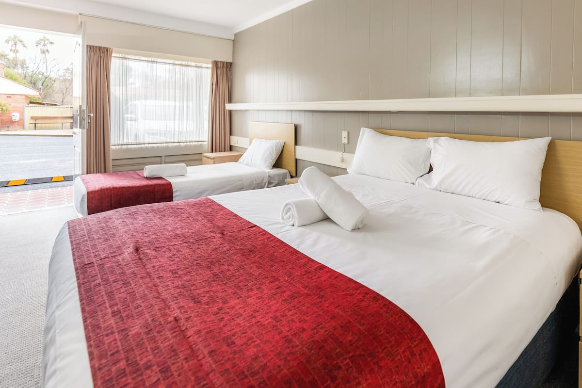 A hotel room with two beds, a large window, and a view of the street outside.
