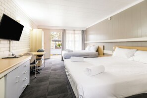 A hotel room with a bed, a desk, a chair, a television, and a window.