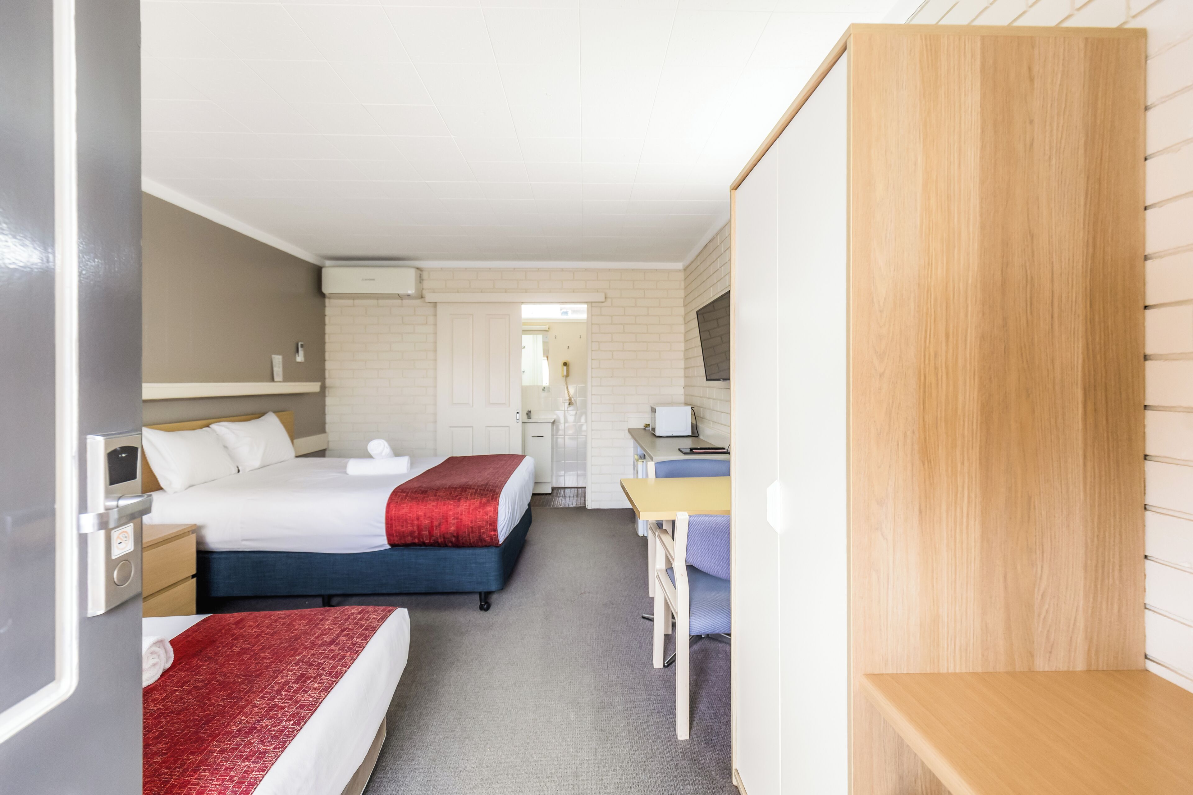 A hotel room with two beds, a desk, and a chair.