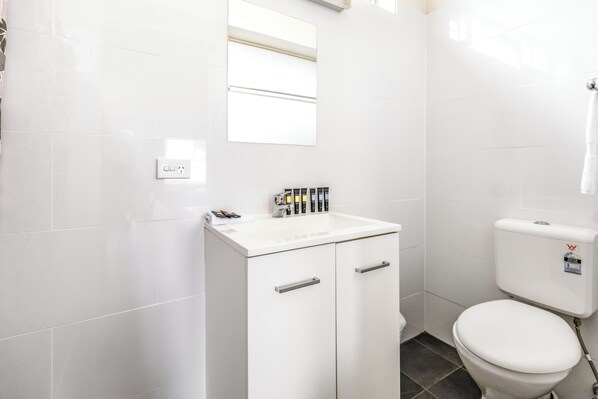 A bathroom with a white sink, mirror, and toilet.