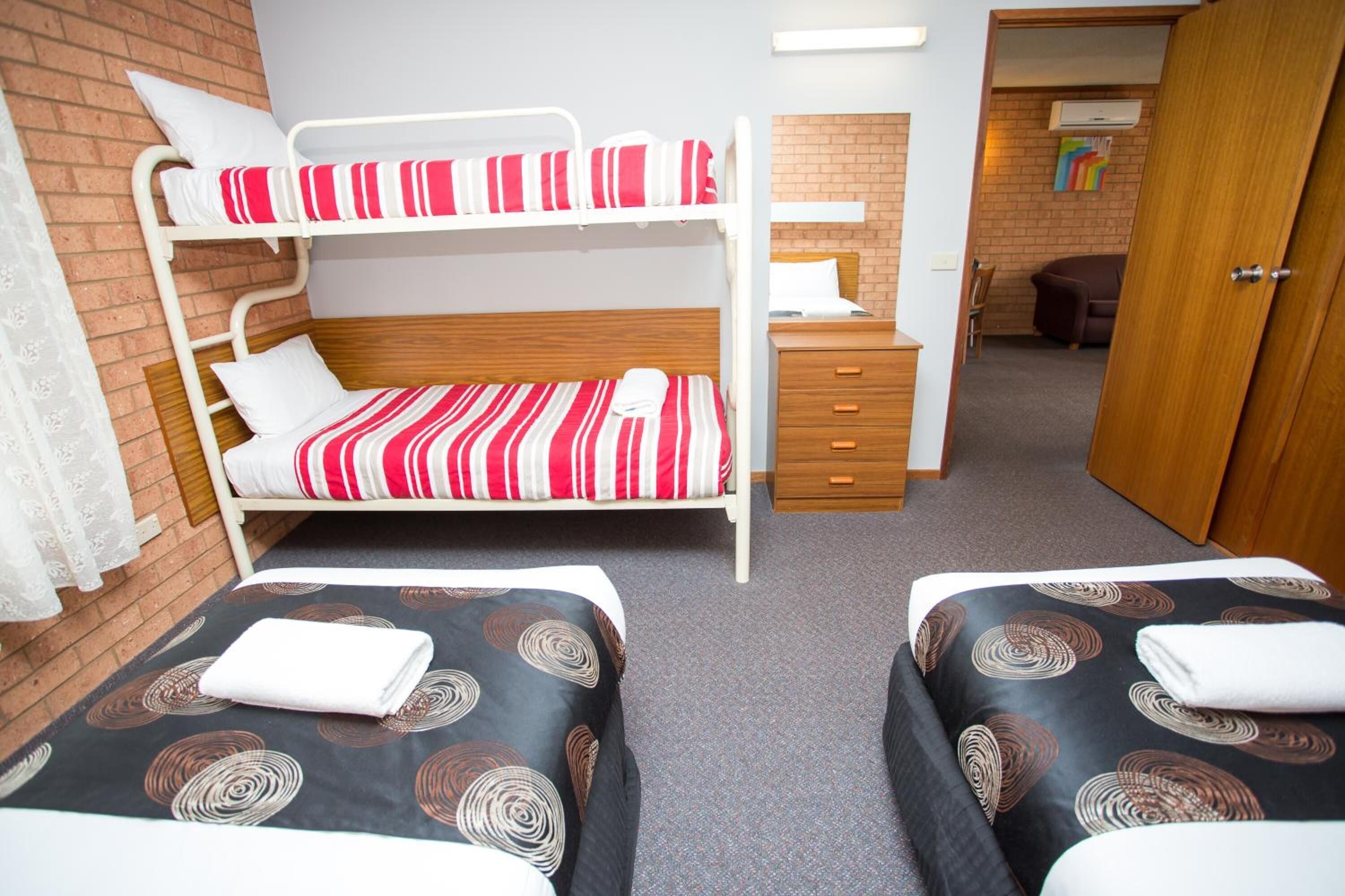 A room with bunk beds, a wooden dresser, and a small desk.