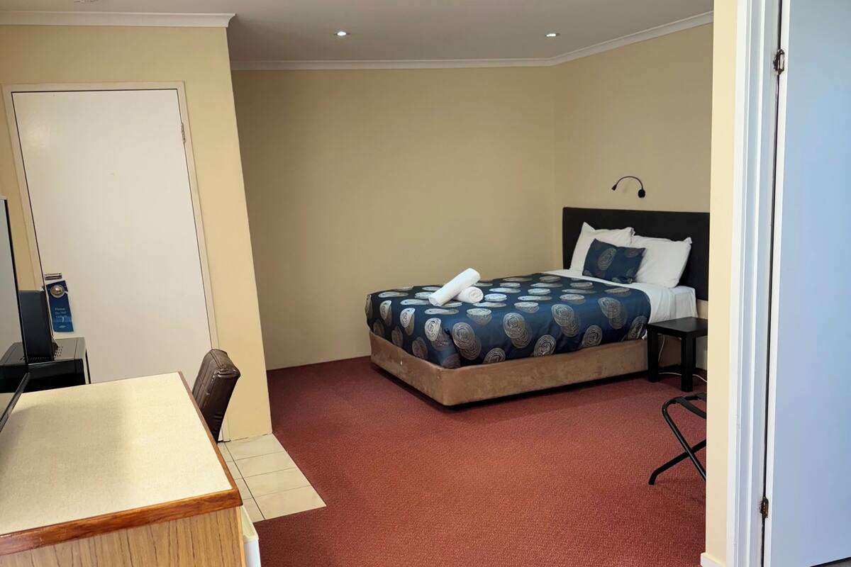 A hotel room with a bed, a desk, and a chair.