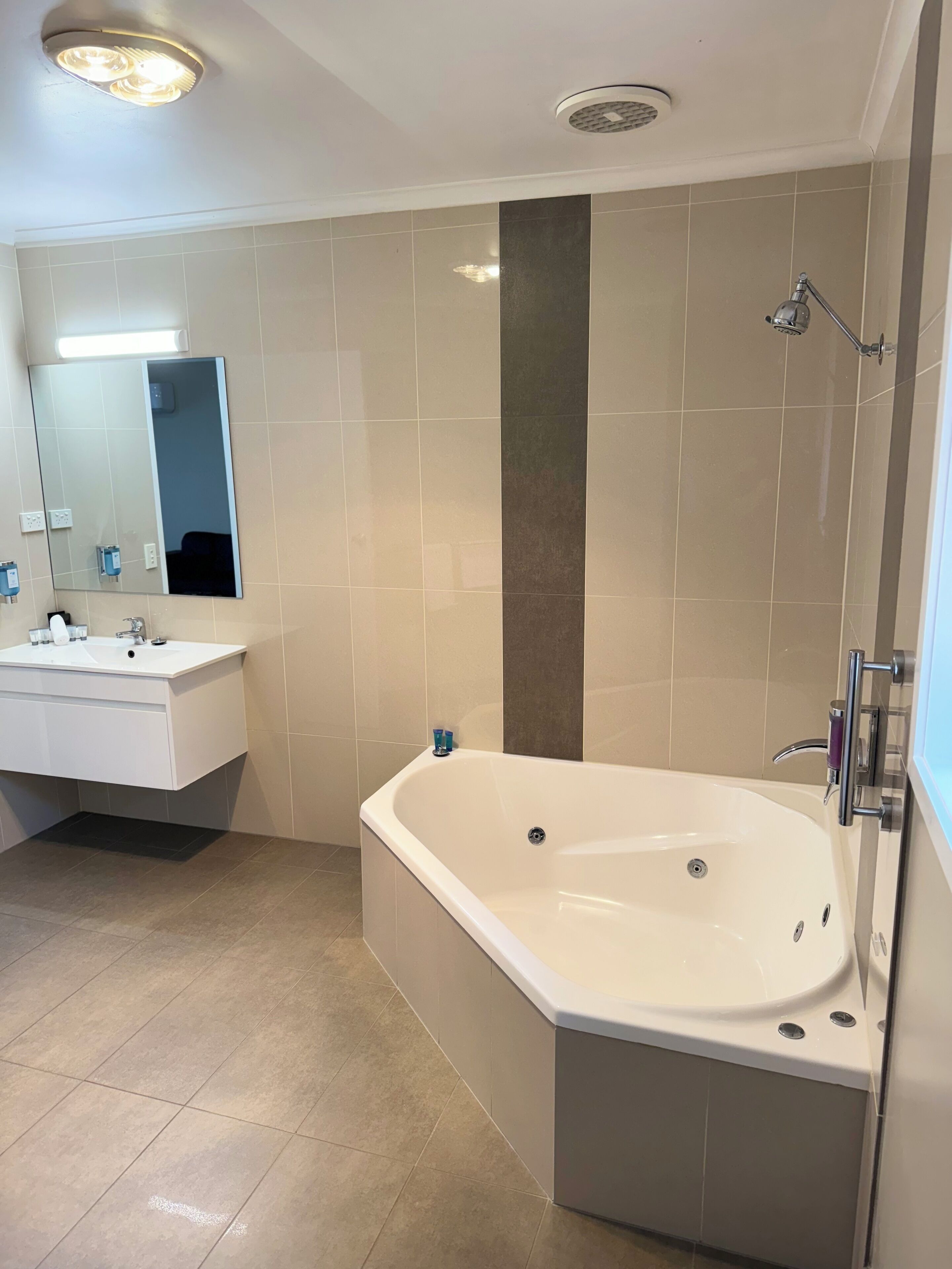 A modern bathroom with a large bathtub, a vanity with a mirror, and a shower area.