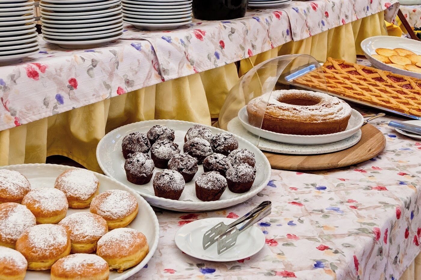 A buffet table with various desserts including muffins, a cake, and a lattice-topped pie.