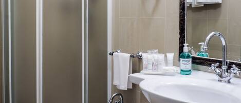 A bathroom with a shower, bidet, sink, and a hairdryer mounted on the wall.
