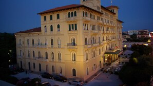 A large, multi-story building with a central courtyard, featuring balconies and a flagpole. - Grand Hotel Royal (Viareggio)