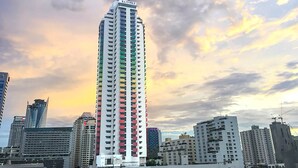 A tall, multi-story building with a distinctive color pattern on its facade, surrounded by other high-rise buildings. - Baiyoke Suite Hotel (Bangkok)