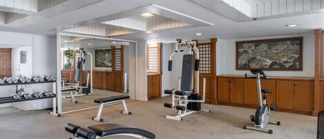 A gym with exercise equipment, a mirror, and a large painting on the wall.