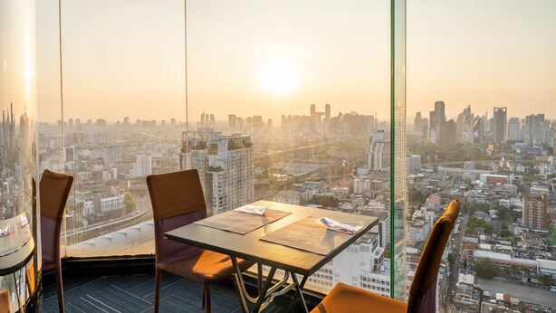 A high-rise room with a panoramic city view, a table with chairs, and a glass partition. - Baiyoke Suite Hotel (Bangkok)