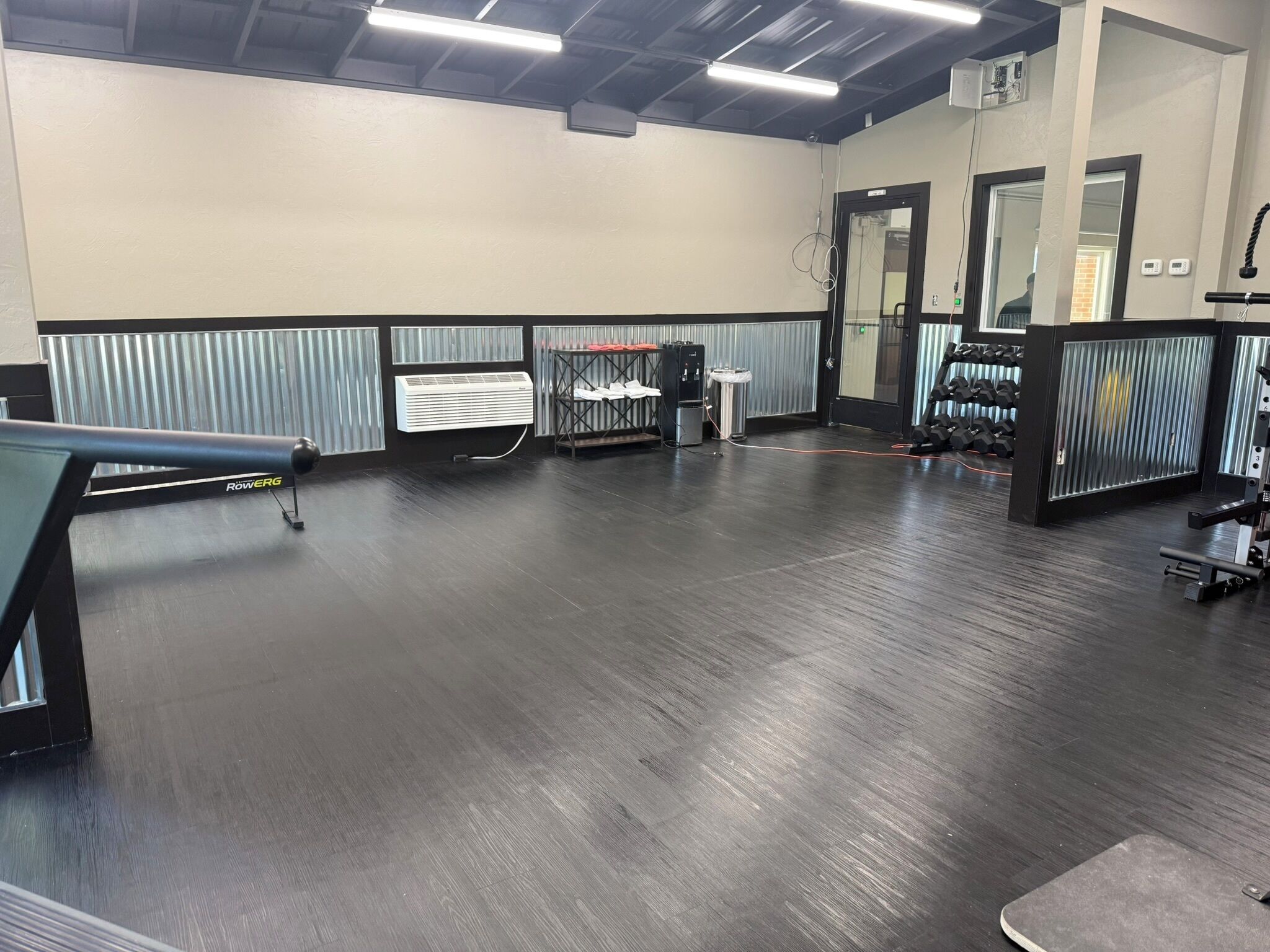 A gym with a rowing machine, weight racks, and a mirror.
