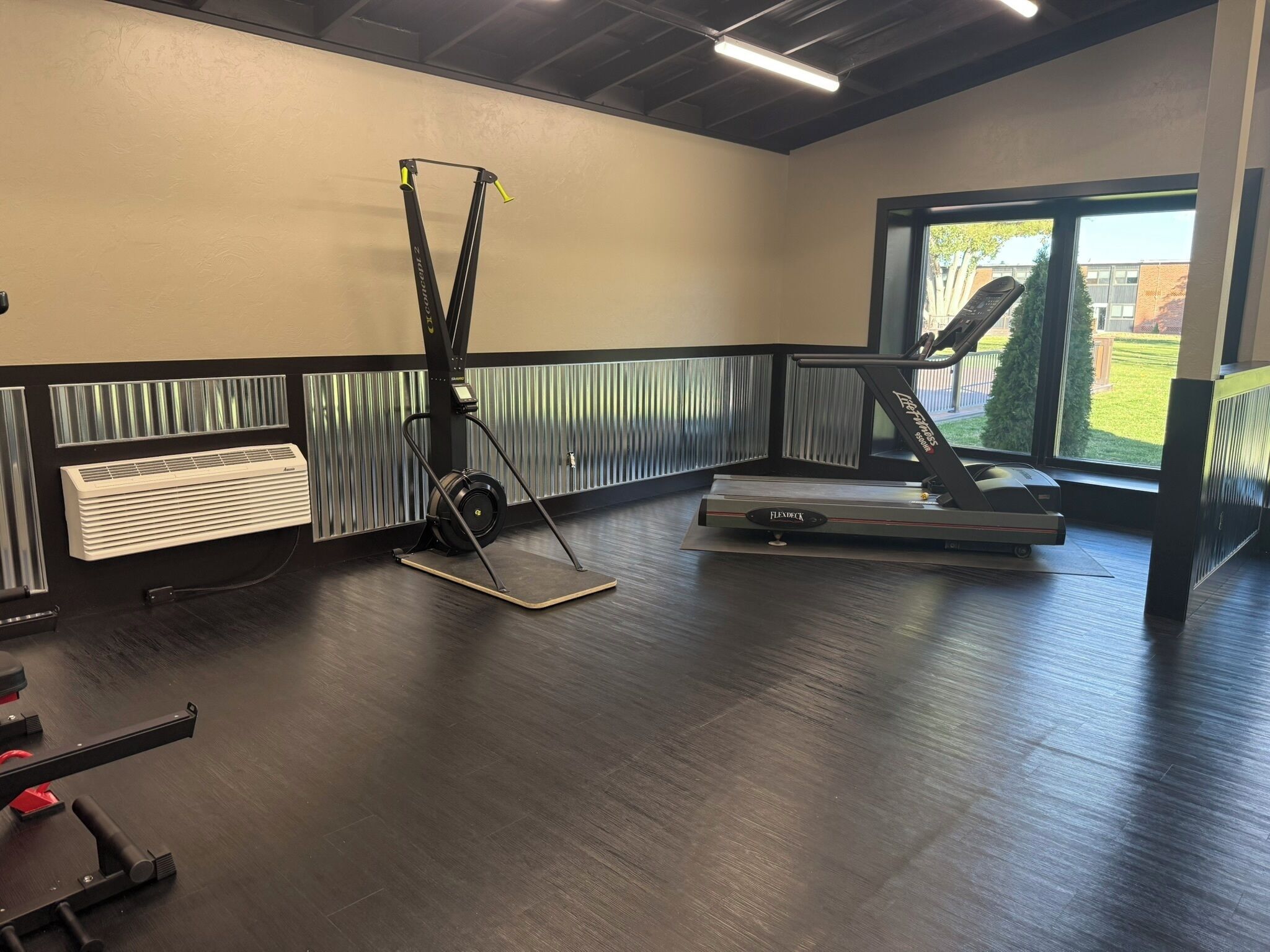 A gym with a treadmill, a stationary bike, and a ceiling-mounted exercise machine.