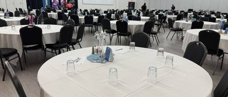 A conference room with round tables, chairs, and a presentation screen.