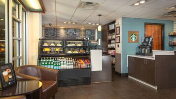 Interieur van een koffiebar met zitplaatsen, een vitrine met gebak, een menubord en Starbucks branding.