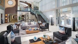 A spacious lobby with a modern design, featuring a central staircase, multiple seating areas, and a large window offering a view of the outside. - DoubleTree by Hilton Hotel Chattanooga Downtown (Chattanooga)