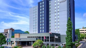 A DoubleTree by Hilton hotel with a modern design, a landscaped entrance, and a clear blue sky. - DoubleTree by Hilton Hotel Chattanooga Downtown (Chattanooga)