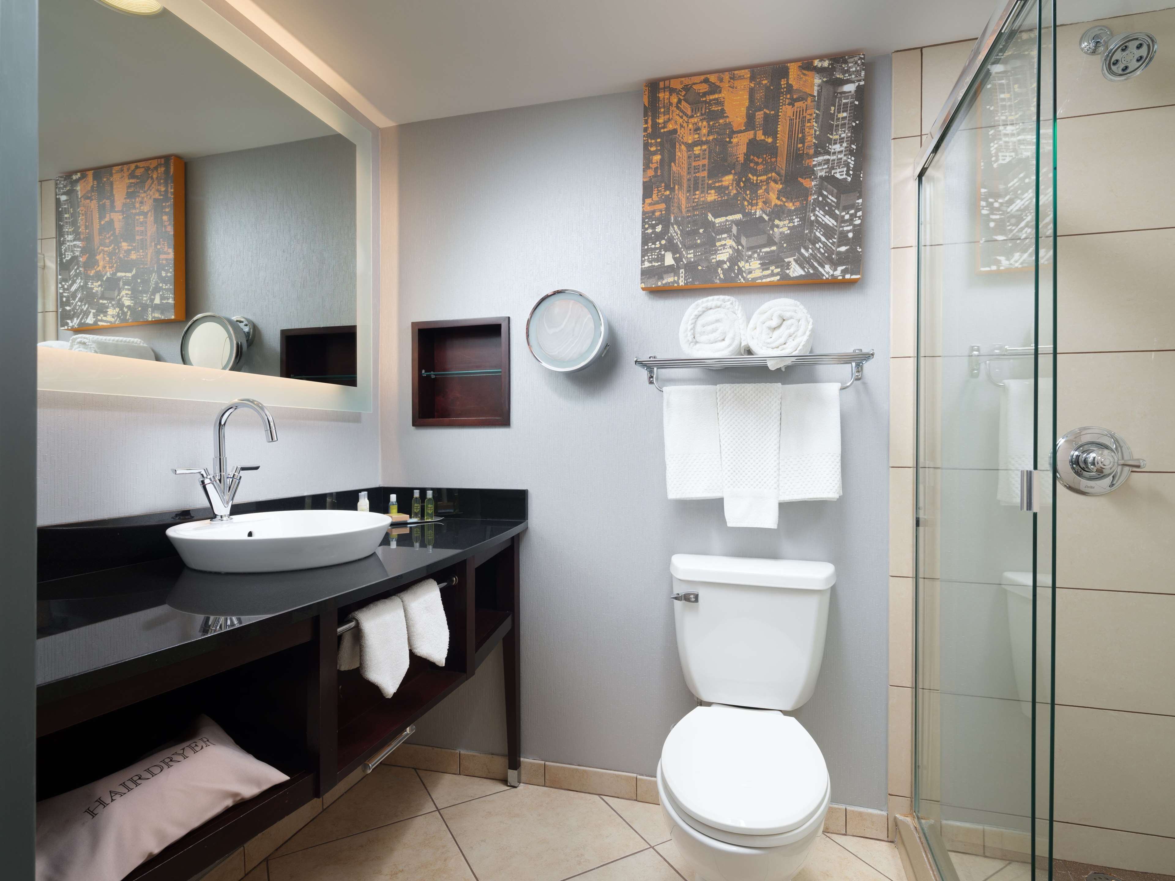 A modern bathroom with a sink, mirror, toilet, and glass shower enclosure.