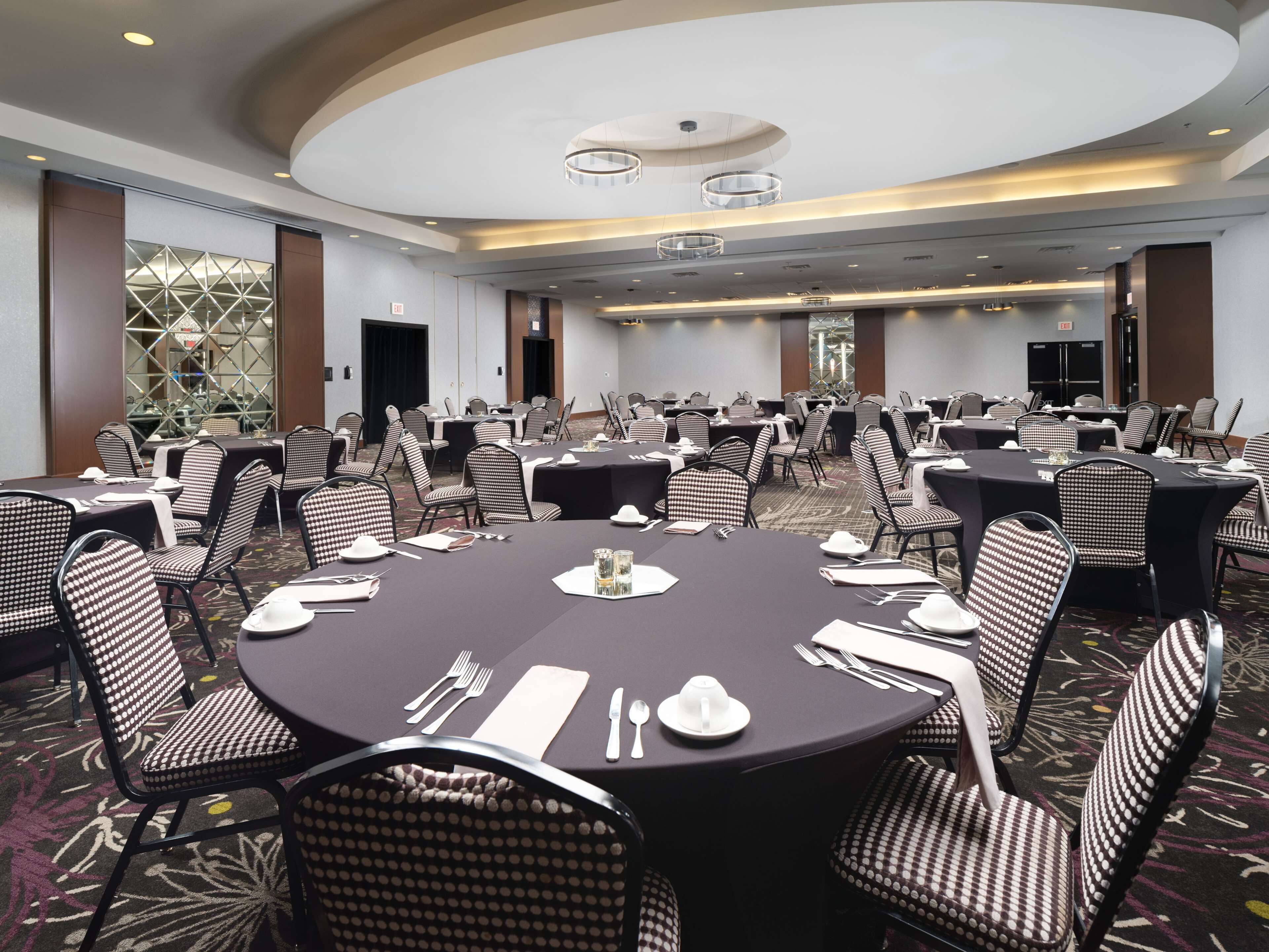 A conference room with round tables, checkered chairs, and a carpeted floor.